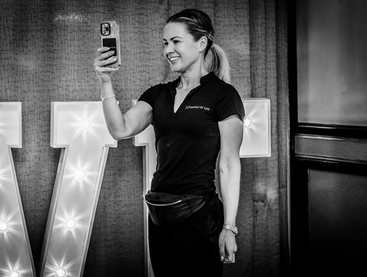 Gail Irvine - owner of Content by Gail, a Scottish wedding content creator - smiles as she snaps a picture at a wedding.